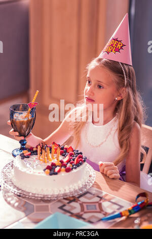 Blonde Mädchen Müde beim Sitzen mit ihrem Geburtstag Kuchen Stockfoto