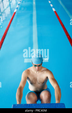 Foto von sportlichen Schwimmer Mann in blauen Deckel an der Seite im Pool