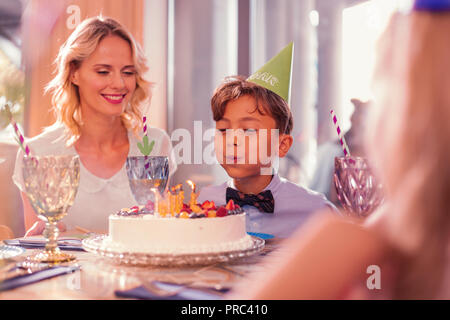 Happy Birthday Boy blasen Kerzen und seine Mutter lächelnd Stockfoto