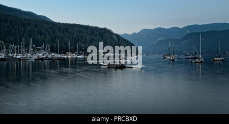 Deep Cove sand Strand gut zum Schwimmen, die alle entlang des Wassers im Dorf gepflastert ist Weg mit der Deep Cove Pier und die Marine in der Mitte Stockfoto