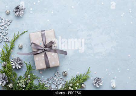 Weihnachten Zusammensetzung auf blauem Hintergrund. Rahmen von Juniper Zweige, silber Dekor und dekorierte Geschenkbox. Ansicht von oben, kopieren. Stockfoto