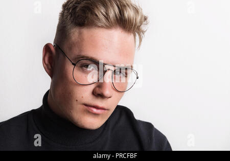 Nahaufnahme Porträt einer selbstbewussten jungen Mann in einem Studio, Brille trägt. Stockfoto