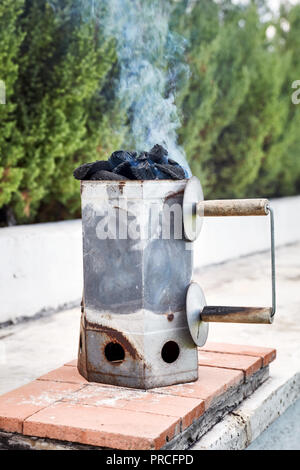 Smoking charcoal chimney starter bucket for barbecue in a backyard garden Stockfoto