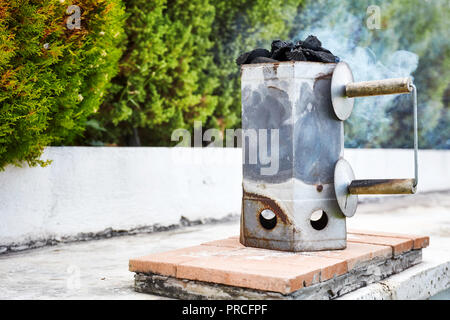 Smoking charcoal chimney starter bucket for barbecue in a backyard garden Stockfoto