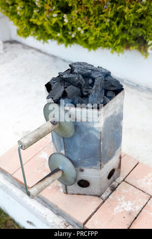 Smoking charcoal chimney starter bucket for barbecue in a backyard garden Stockfoto