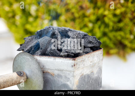 Smoking charcoal chimney starter bucket for barbecue in a backyard garden Stockfoto