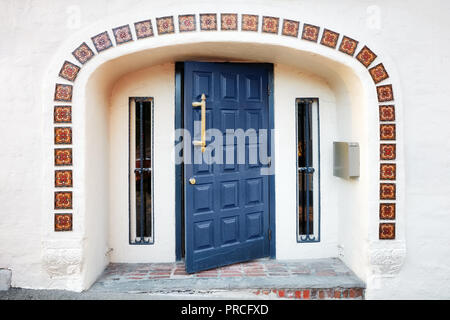 Halb offene blaue Holztür, dekorative Fliesen, Fenster und beigefarbenen Wänden der Eingang eines alten Gebäudes Stockfoto