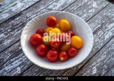 Eine Schüssel gemischten roten und gelben kleinen Tomaten auf einem Holztisch Stockfoto