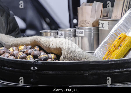 Geröstete Kastanien und Mais-auf-die-Cob zum Verkauf bei einem Straßenhändler Warenkorb. Stockfoto