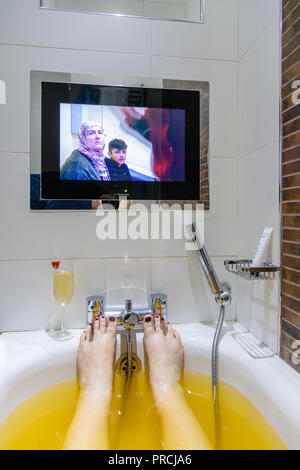 Fernseher an der Wand am Ende einer Badewanne in einem Hotel. Stockfoto