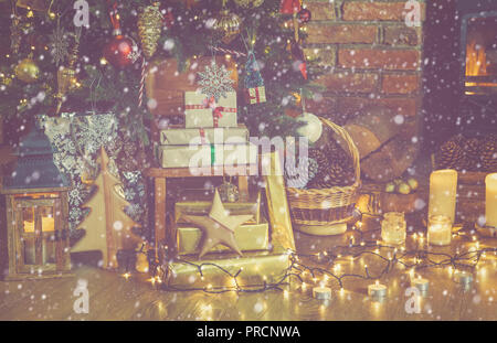 Stapel Geschenke unter beleuchtete Weihnachtsbaum mit Kugeln und Ornamente, Laterne, Sterne, Girlanden, lichter Kamin, Schnee, selektiver Fokus, getönt Stockfoto