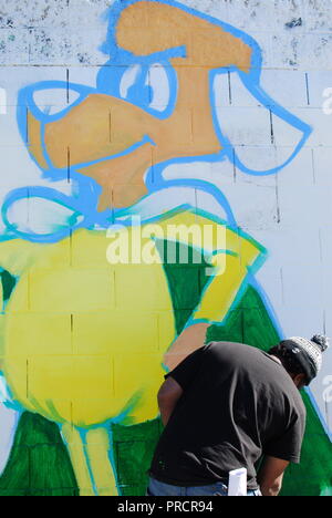 Ein Künstler arbeitet auf einem Gemälde von Underdog auf San Pablo Avenue in der Nähe der 30. Straße in West Oakland. Stockfoto