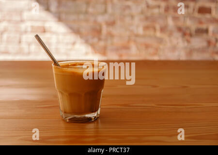 Flache weiße Kaffee in transparentem Glas auf hölzernen Tisch. Es ist Espresso-Kaffee trinken, bestehend aus Espresso mit schaumstofftasche gedämpfte Milch mit kleine Bläschen mit einer glänzenden oder samtige Konsistenz. Stockfoto