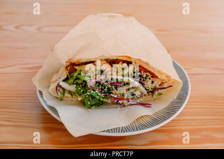 Close-up shaurma Sandwich chicken Roll in Pita mit frischem Gemüse auf dem Teller in Fast food Cafe serviert. Stockfoto