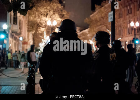 California Highway Patrol Offiziere beobachten Demonstranten in der Nähe der Ecke zur 9. und Washington Straßen in der Innenstadt von Oakland nach Donald Trump Wahl. Stockfoto