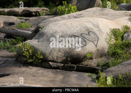 Frieden unterzeichnen und Herzform sprühte auf großen Felsen Stockfoto