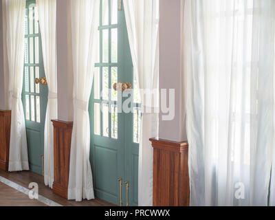 Licht durch das Sehen durch die weißen Vorhängen von außen mit grünen Holztüren in der zeitgenössischen Vintage House. Stockfoto