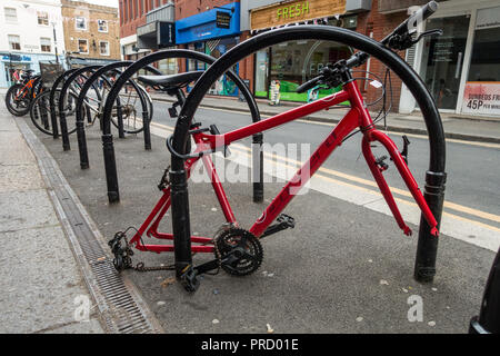 Ein Rad, das bis zu einem Fahrradträger in Windsor gesperrt ist hat Räder in einem Akt der Kleinkriminalität gestohlen. Der Rahmen ist links verlassen. Stockfoto