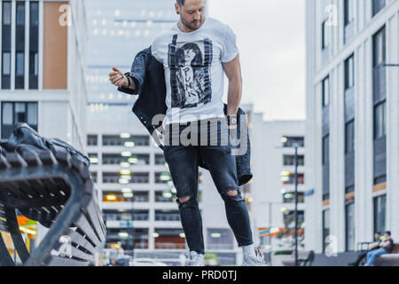 Ferner Plan des Menschen auf seine schwarze Jacke und neben Bank. Stockfoto