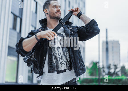 Junger attraktiver Mann in schwarzen Jeans Jacke stehend auf stadtbild Hintergrund. Stockfoto