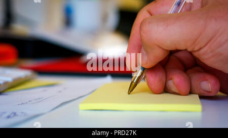 Männliche hand Schreiben mit einem Stift auf einem gelben Blatt Stockfoto
