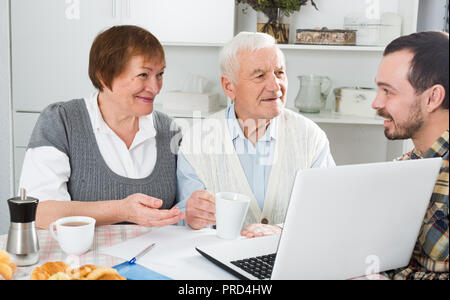 Lächelnd Großeltern und Enkel sehen Sie interessante Neuigkeiten über Internet auf dem Laptop zu Hause Stockfoto