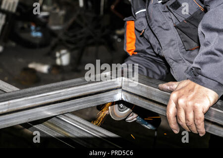 Handwerker Sägen von Metall mit dem Winkelschleifer in der Werkstatt. Schleifen von Metall mit Funken fliegen. Stockfoto