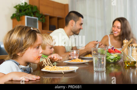 Lächelnd Familie mit zwei kleinen Töchtern essen Spaghetti mit am Tisch. Fokus auf Mädchen Stockfoto