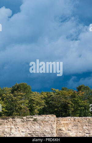 Dunkler Himmel und Wolken Hintergrund mit Bäumen und Kalksteinbruch Felswand im Herbst Landschaft Stockfoto