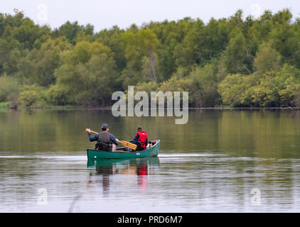 BOSSIER PARISH, LA, USA, SEPT. 29, 2018: ein Mann und eine junge werden von hinten in ein Kanu auf einem schönen, ruhigen See während einer Fangreise gesehen. Stockfoto