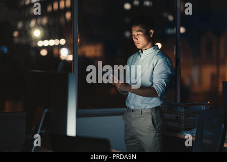 Asiatische Geschäftsmann mit einem digitalen Tablet spät in der Nacht Stockfoto