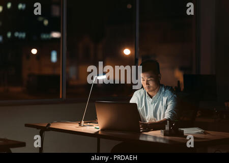 Asiatische Geschäftsmann arbeiten allein in einem dunklen Büro bei Nacht Stockfoto