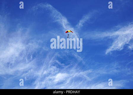 Hell Grün Fallschirm Vordach und Fallschirmspringer vor dem Hintergrund einer verschwommenen weiße Wolken und blauer Himmel. Tandem Master mit Passagier flyin Stockfoto