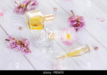 Flaschen Parfüm mit Blumen auf weißem Hintergrund Stockfoto