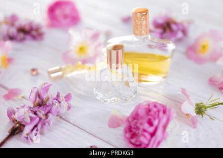 Flaschen Parfüm mit Blumen auf weißem Hintergrund Stockfoto