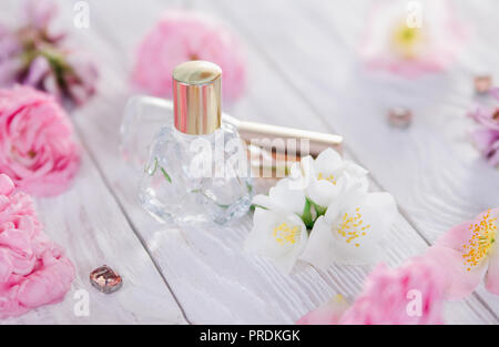 Flaschen Parfüm mit Blumen auf weißem Hintergrund Stockfoto