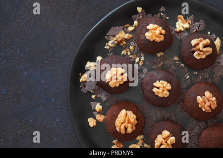 Rum Kugeln sind die Trüffel - wie Konfektion von Süß, dichten Kuchen mit dem Geschmack von Schokolade und Rum. Flach der dunklen Platte rum Kugeln mit wallnuts auf dar Stockfoto