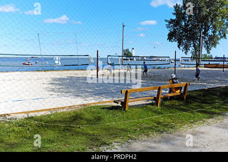 Mit Segelbooten im Hintergrund, ein früher Herbst Volleyball Spiel passiert in Wendy Park am Ufer des Lake Erie in Cleveland, Ohio, USA. Stockfoto