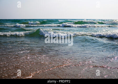 Stürmische See an einem sonnigen windigen Tag. Große Wellen mit weißen Schaum auf dem Kamm steigen über die Oberfläche des Wassers und zum Ufer laufen. Wunderschönes b Stockfoto