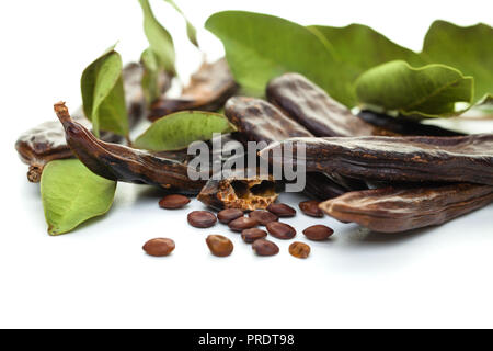 Johannisbrot bean. Gesunde organische süße Johannisbrot Schoten mit Samen und Blätter auf weißem Hintergrund Stockfoto