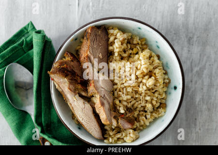 Gesundes Essen Porridge mit gebackenen Putenfleisch in Schüssel auf weißem Holz- Tabelle, Ansicht von oben. Gesunde Ernährung Konzept Stockfoto