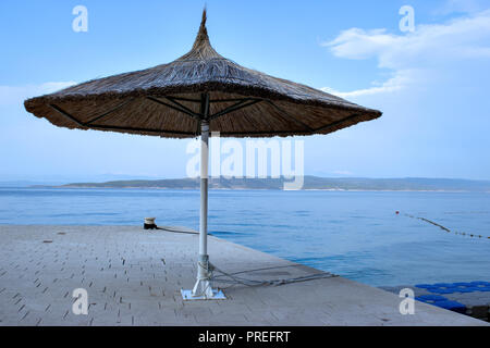 Noch immer leben mit einem isolierten Bambus Sonnenschirm am Strand am Meer. Stockfoto