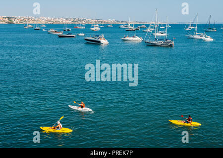 Cascais, Portugal - Sept 29, 2018: Personen, Kajakfahren an der Bucht von Cascais im Sommer mit luxuriösen Yachten im Hintergrund Stockfoto