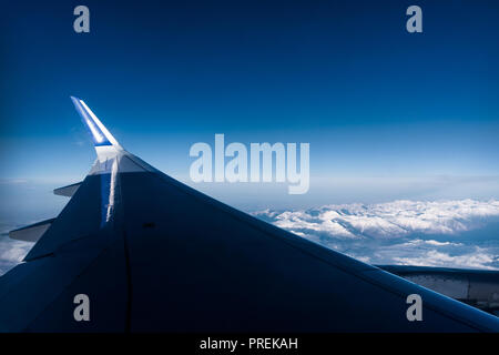 Wolken und Himmel, als durch das Fenster eines Flugzeugs gesehen. Anreise mit dem Flugzeug. Über den Wolken. Stockfoto