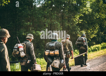 Re-enactors gekleidet, wie Deutsche Wehrmacht Infanterie Soldat im Zweiten Weltkrieg marschiert zu Fuß entlang der Forststraße im Sommer Tag. Stockfoto