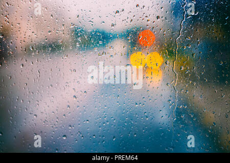 Wasser Tropfen Regen auf Glas Hintergrund. Straße Bokeh Lichter aus. Herbst abstrakten Hintergrund Wetter Konzept Stockfoto