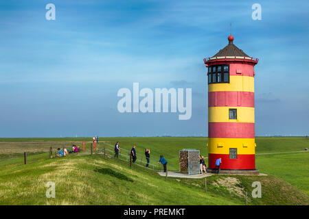 Pilsumer Leuchtturm in Ostfriesland, Touristen gehen, sitzen auf dem Deich und Fotografieren Stockfoto