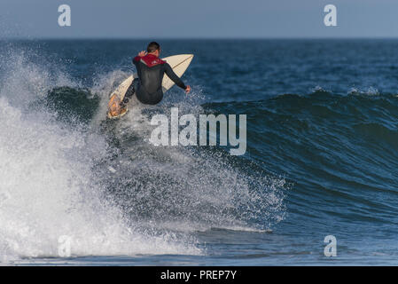 Surfer in voller Neoprenanzug Hits die Welle Lippe mit voller Geschwindigkeit bei Knoll Surfer's, Ventura, Kalifornien am 1. Oktober 2018. Stockfoto