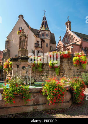 Schloss, Kirche und Brunnen namens Saint Leon auf dem zentralen Platz von Eguisheim Dorf in Frankreich. Eguisheim ist eine Gemeinde im Elsass. Stockfoto