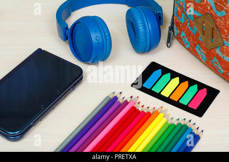 Die Schule liefert. Schule Rucksack, Buch, Buntstifte, ebook, Farbe Lesezeichen und Kopfhörer auf Holztisch. Ansicht von oben. Zurück zum Konzept der Schule. Stockfoto